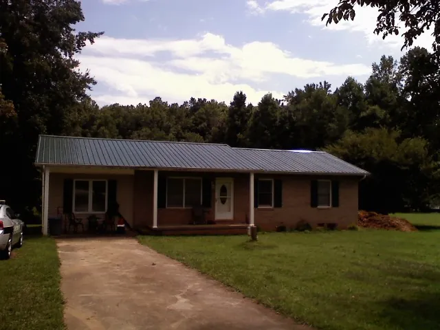 Dark green metal roof on a brick ranch with a covered porch in Mendota