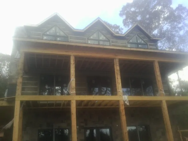 Dormers and porch framing on a large log home under construction — Roof Coating work by our crew in Mendota