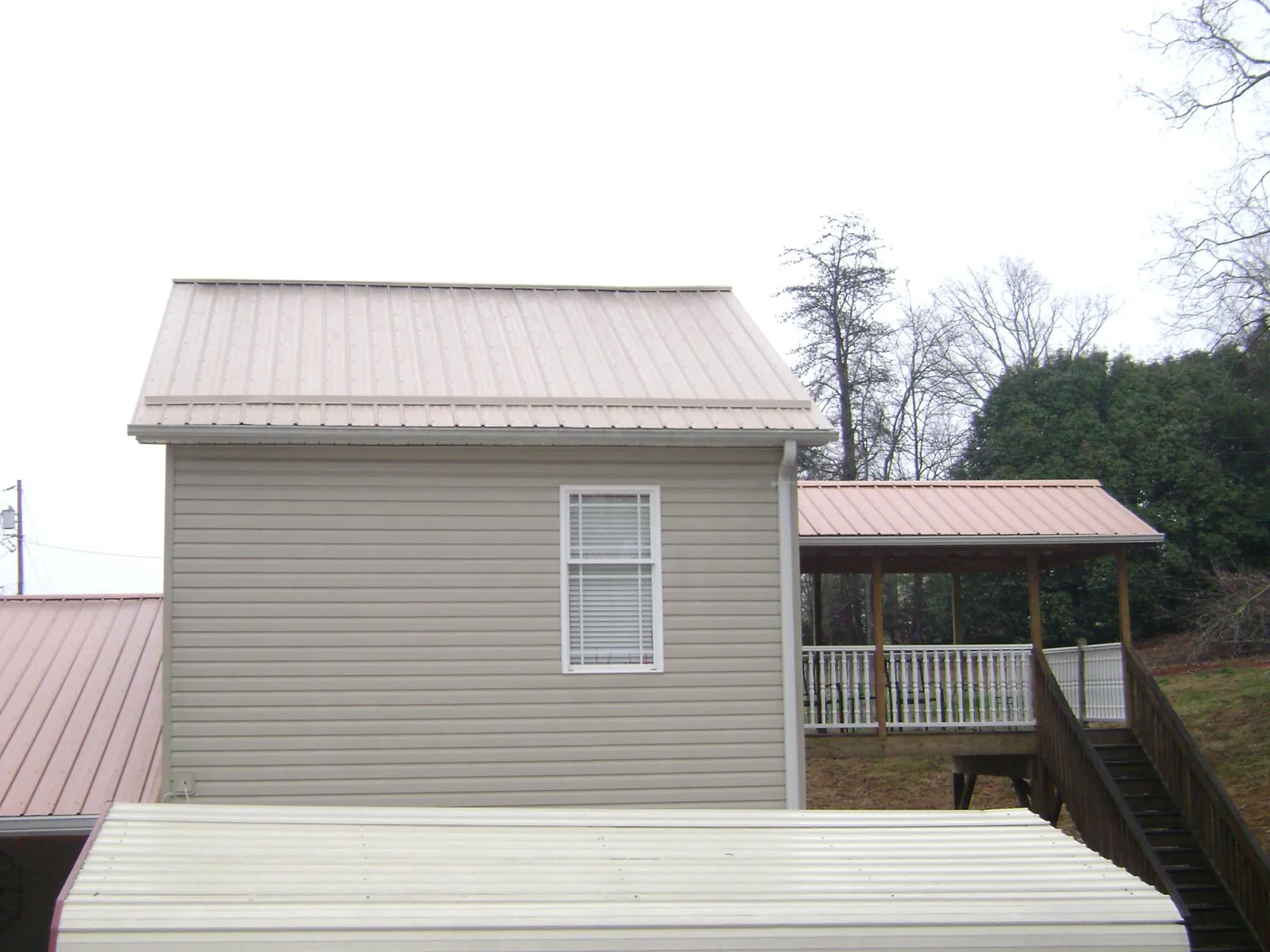 Tan metal roofs on a two story addition and attached porch, from a Roof Replacement job in Mendota